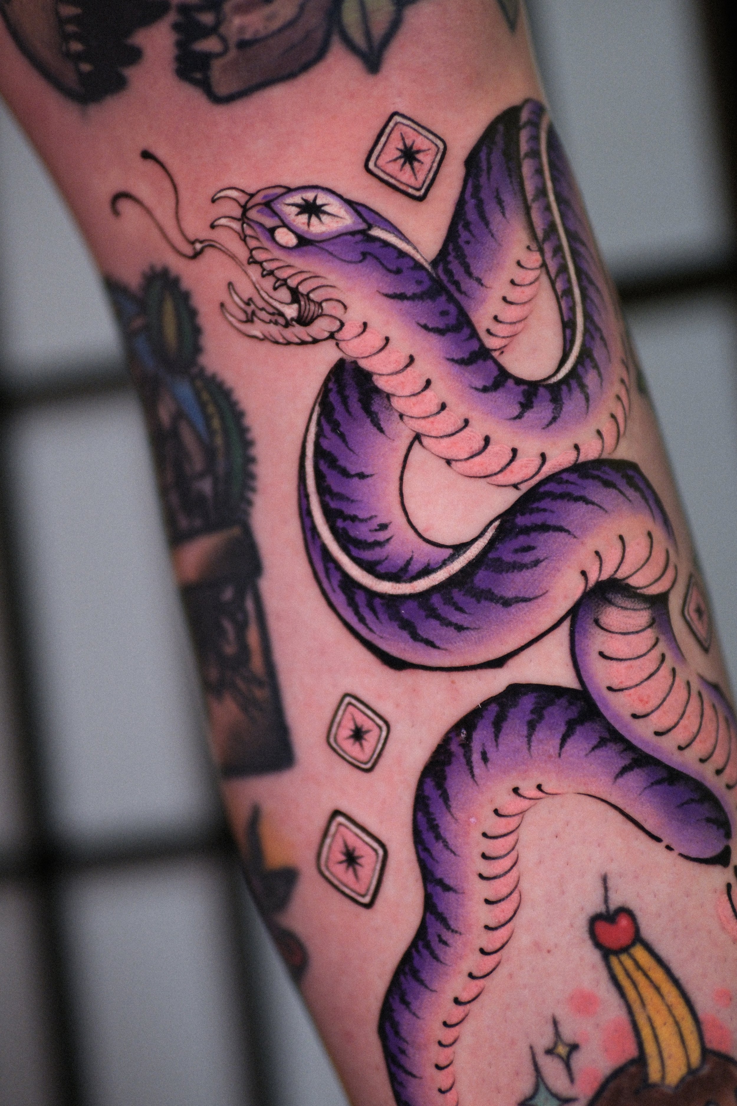 Colorful tattoo of a purple octopus with black and purple details on skin, surrounded by small decorative elements.
