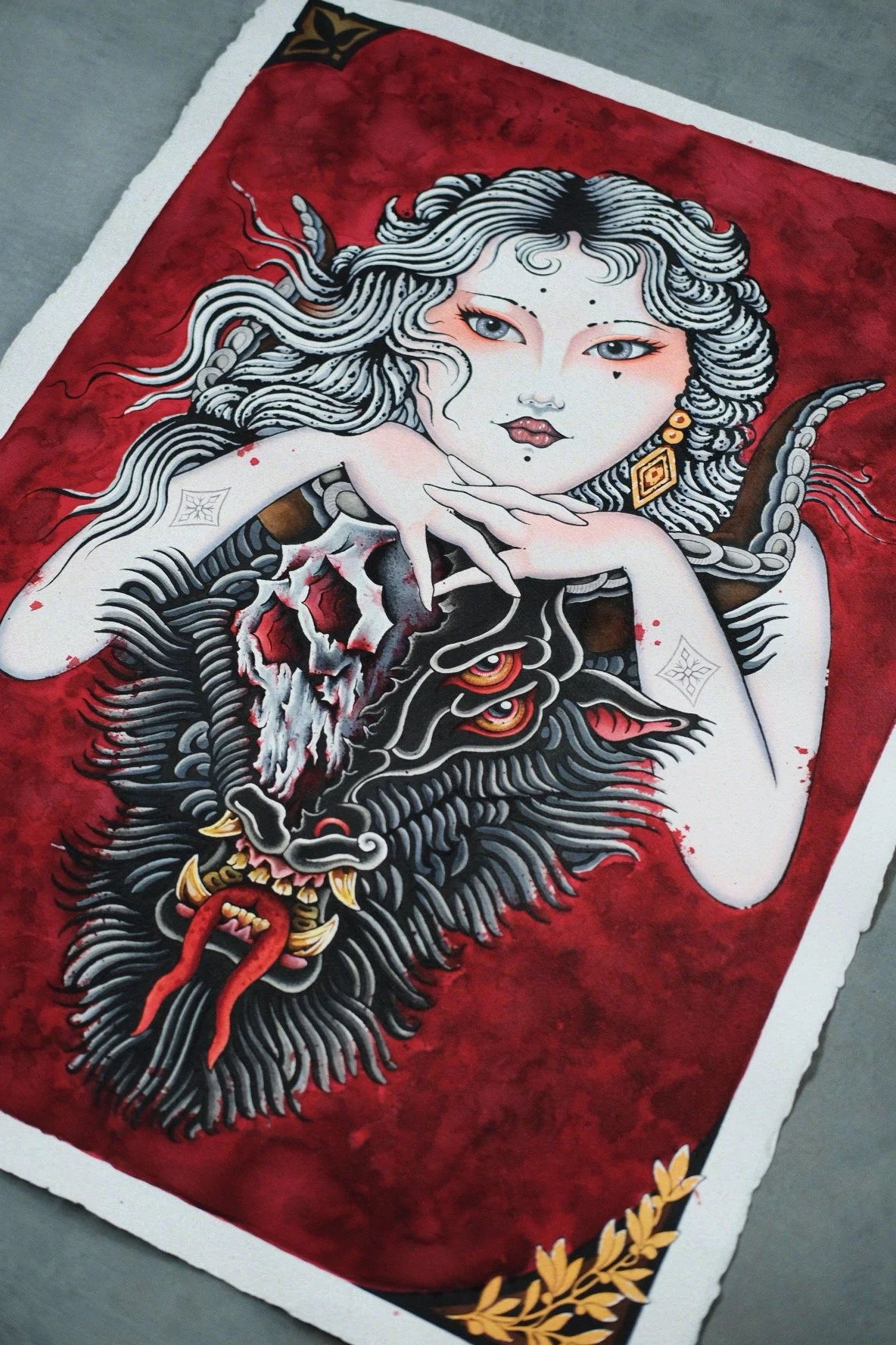 A piece of artwork depicting a woman with long, flowing white hair and pale skin, holding a tiger mask, against a red background with gold accents.