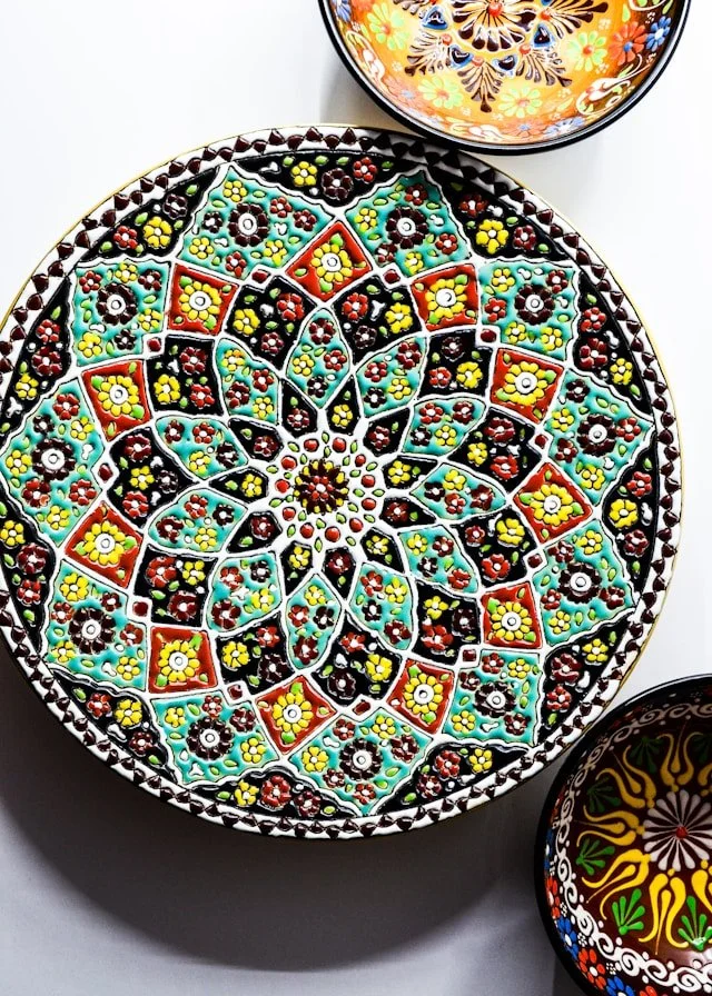 assiette artisanale en terre cuite aux motifs colorés évoquant une approche consciente et holistique de l'alimentation.
