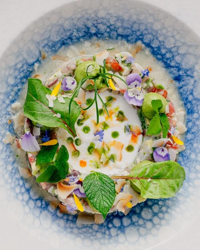 Soupe colorée aux pousses d'épinards et fleurs comestibles illustrant  une alimentation anti-inflammatoire et une approche holistique de la nutrition.