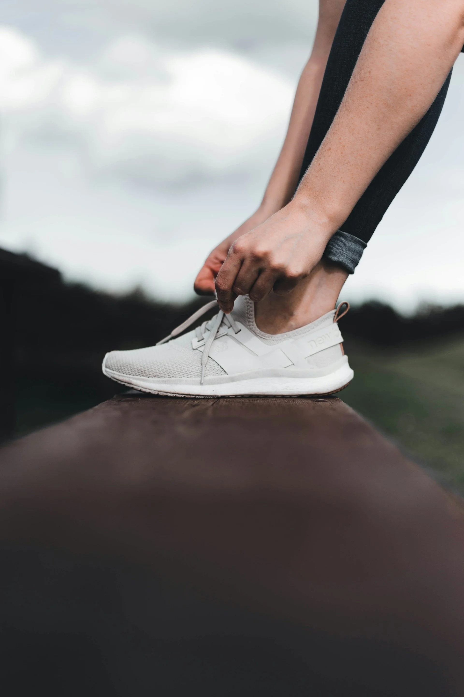 Gros plan sur des mains qui lacent des chaussures de sport pour pratiquer une activité physique adaptée afin de limiter la prise de poids liée aux traitements.