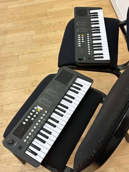 To portable mini keyboards resting on black chairs.