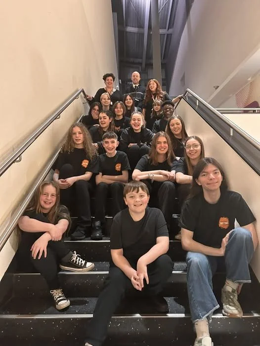 youth choir wearing matching black shirts sitting on the stairs for a group photo before their performance