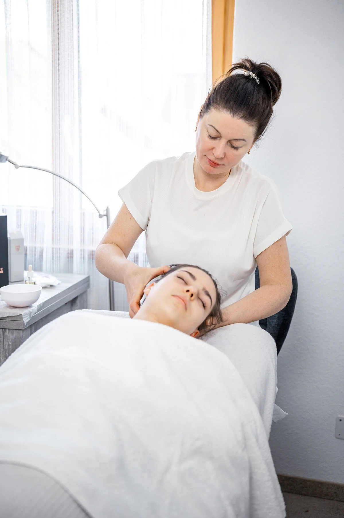 Eine Frau erhält eine Kopfmassage in einem Behandlungszimmer.
