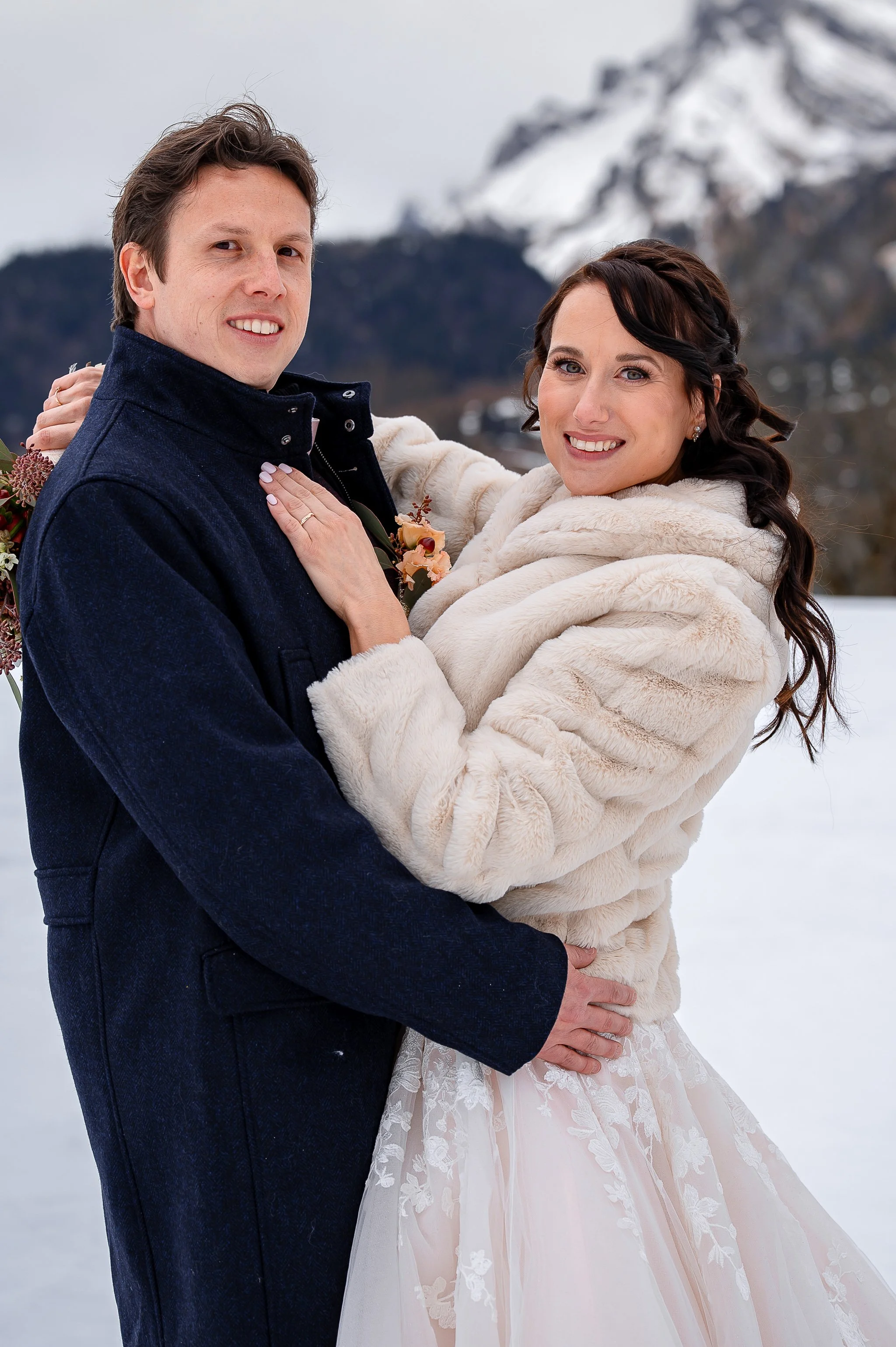 Ein sich küssendes Brautpaar im verschneiten Winter in den Bergen.