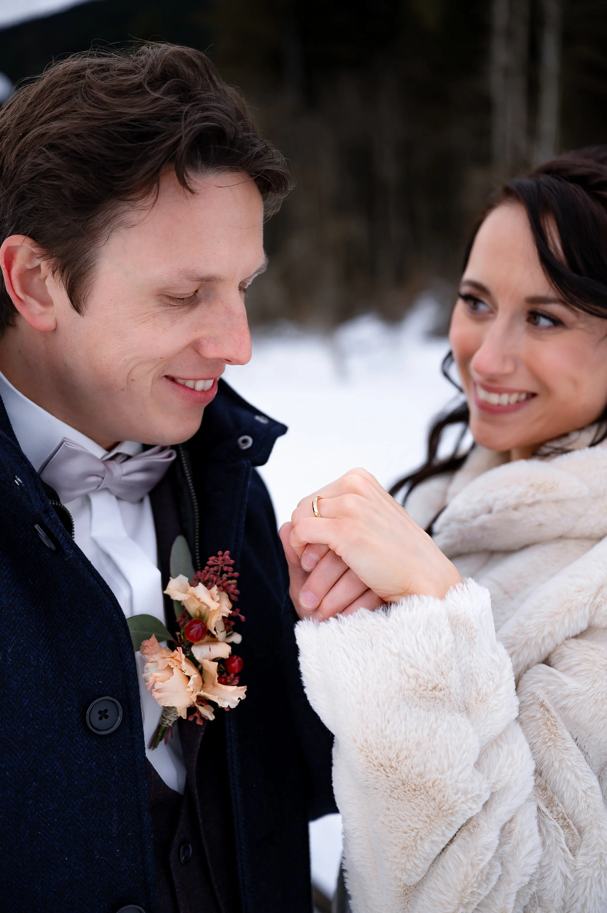 Ein Brautpaar im Schnee, die Händchen halten und sich liebevoll anschauen.