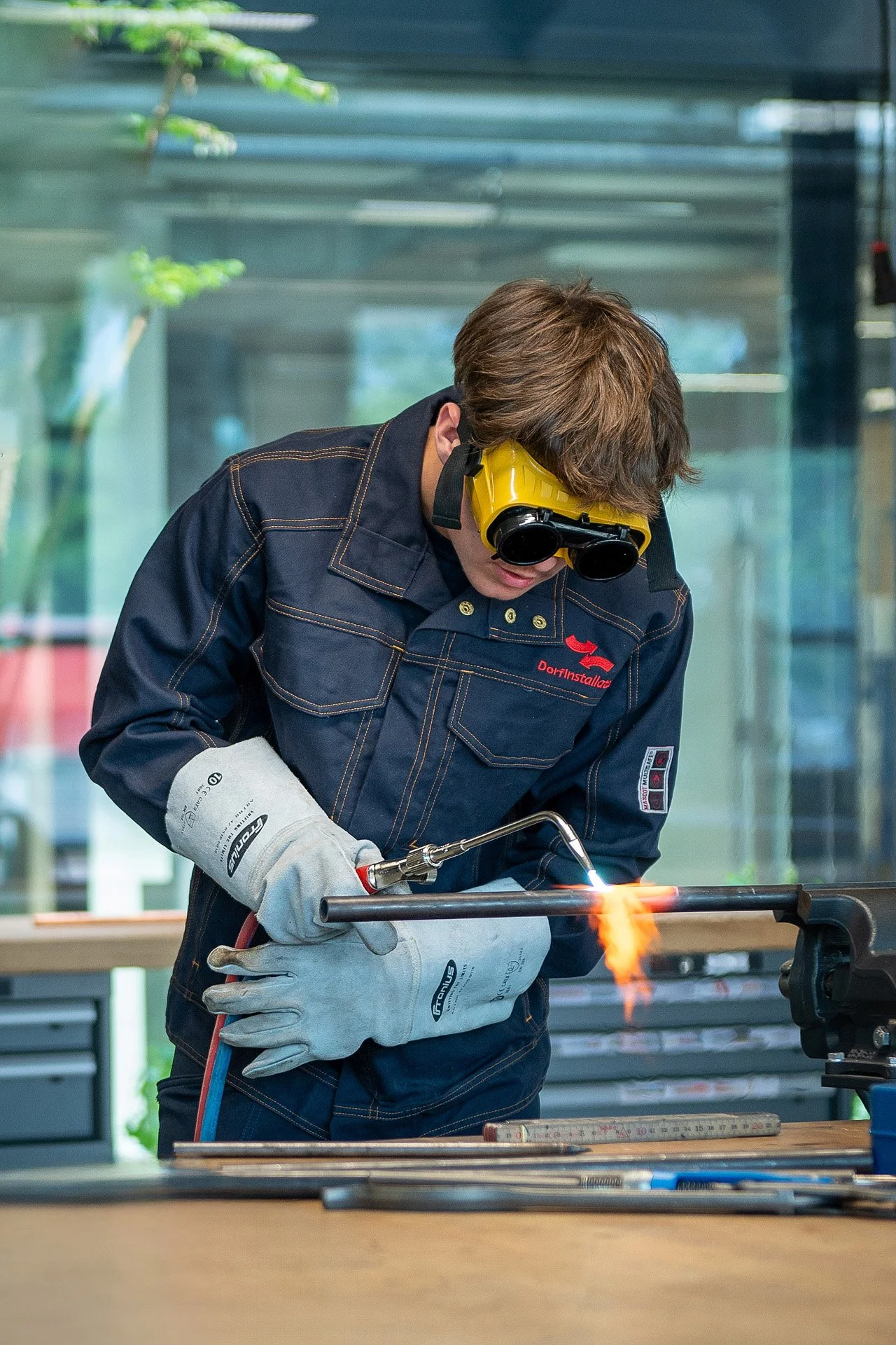 Ein Mann schweißt Metall mit Schutzbrille und Schweißgerät in einer Werkstatt