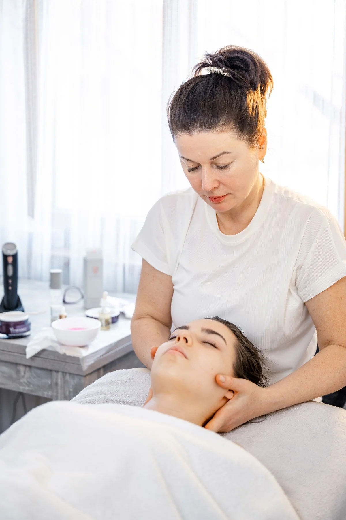 Schönheitsbehandlung im Kosmetikstudio mit Kosmetikerin, die eine Gesichtsmassage bei einer Frau durchführt.