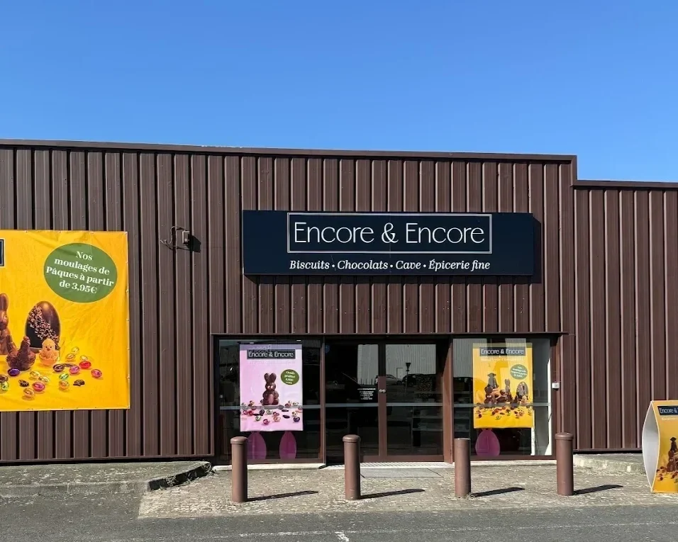 Façade d'un magasin Encore & Encore à Langueux , spécialisé en biscuits bretons , chocolats français, cave et épicerie fine, avec une grande vitrine montrant l'intérieur bien éclairé et des étagères remplies de produits.