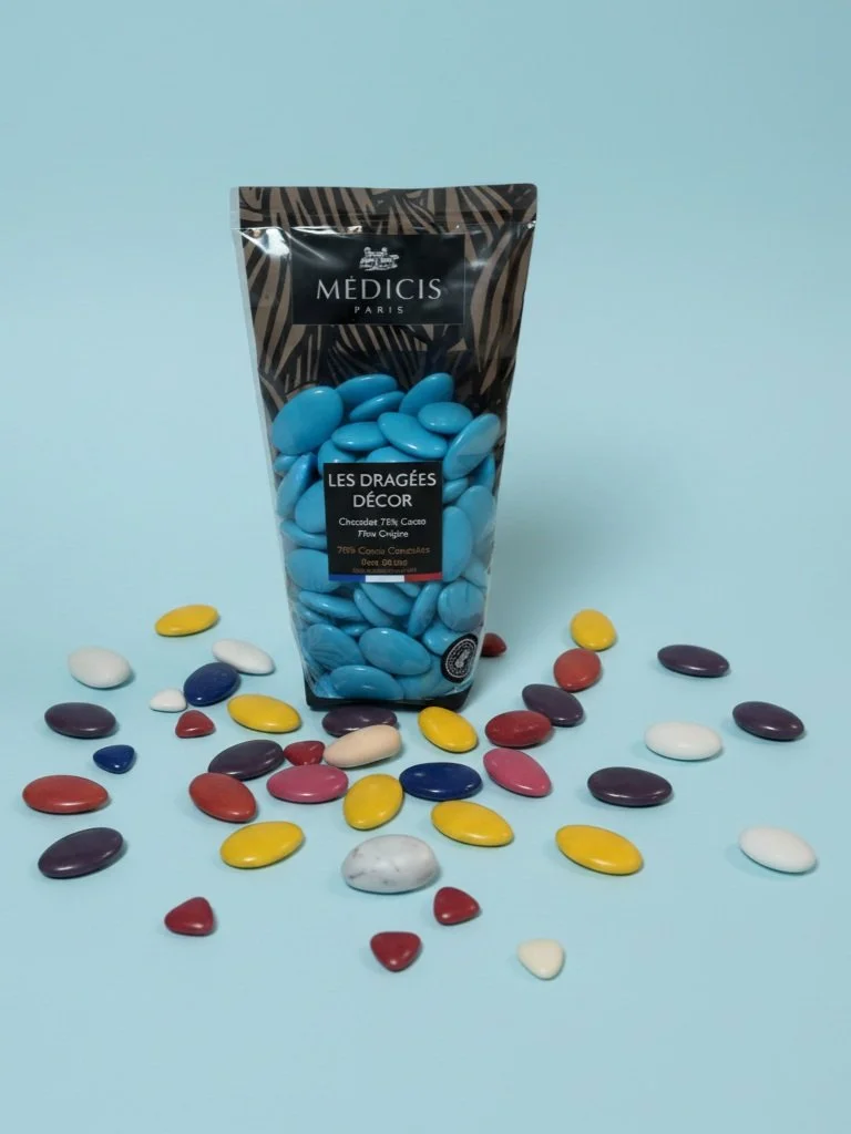 Un paquet de bonbons bleus avec des bonbons de différentes couleurs dispersés autour, sur un fond bleu clair.