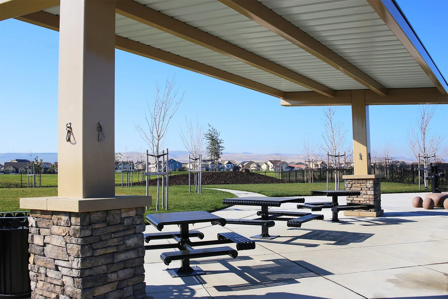A shade structure covers picnic tables in each dog area.