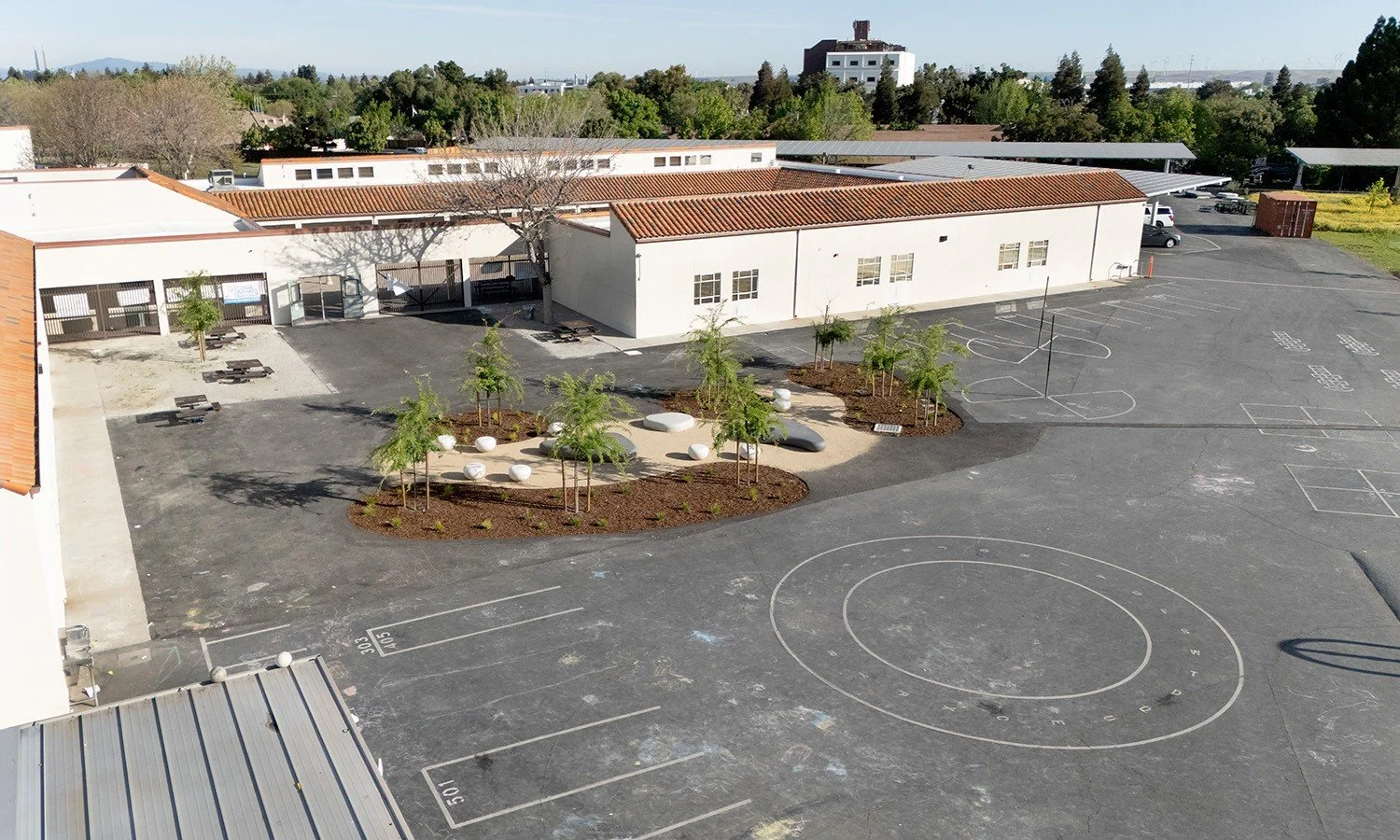 New shade trees and seating areas provide relief from heat in the blacktop area while supporting gathering and everyday student activity.