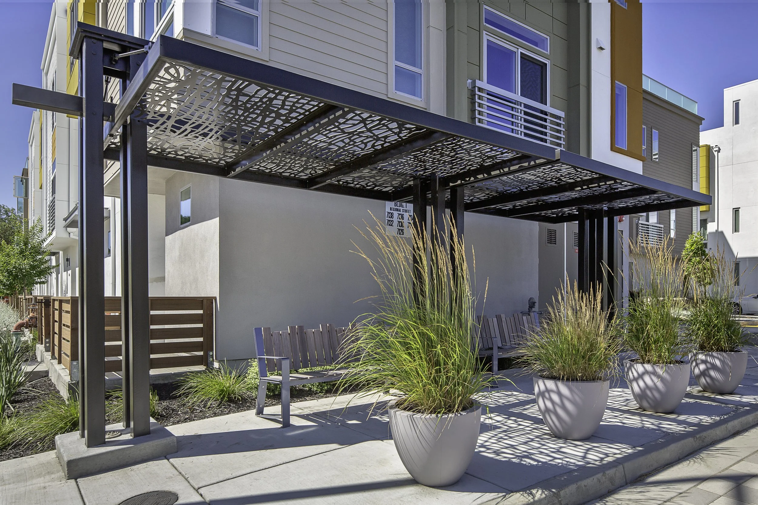 Custom steel shade structures and ornamental grasses soften the urban edge while providing comfortable outdoor gathering spaces.