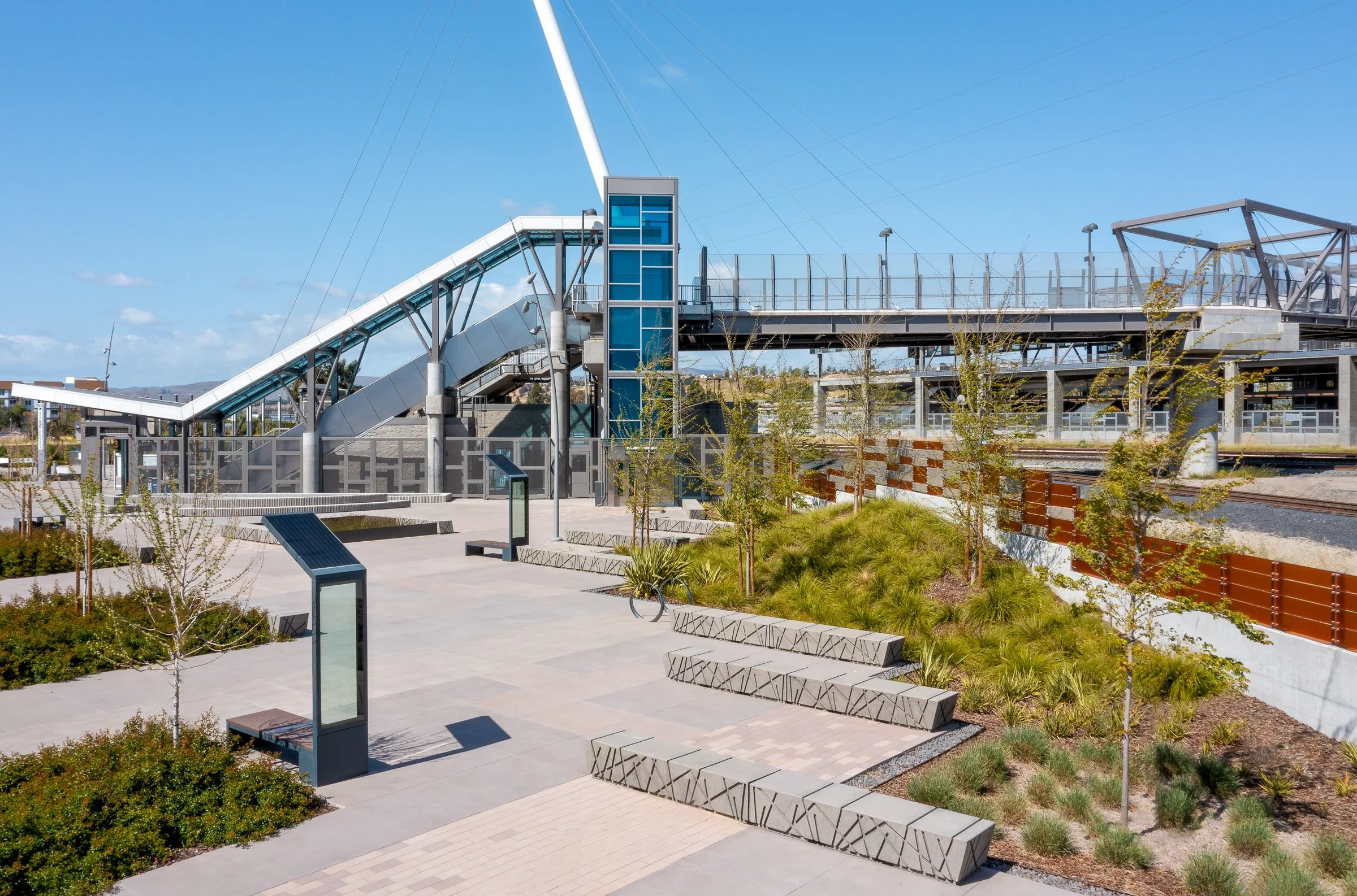 Concrete seat walls and solar charging stations are thoughtfully spaced near vegetation to create a forward-thinking and sustainable "outdoor living room."