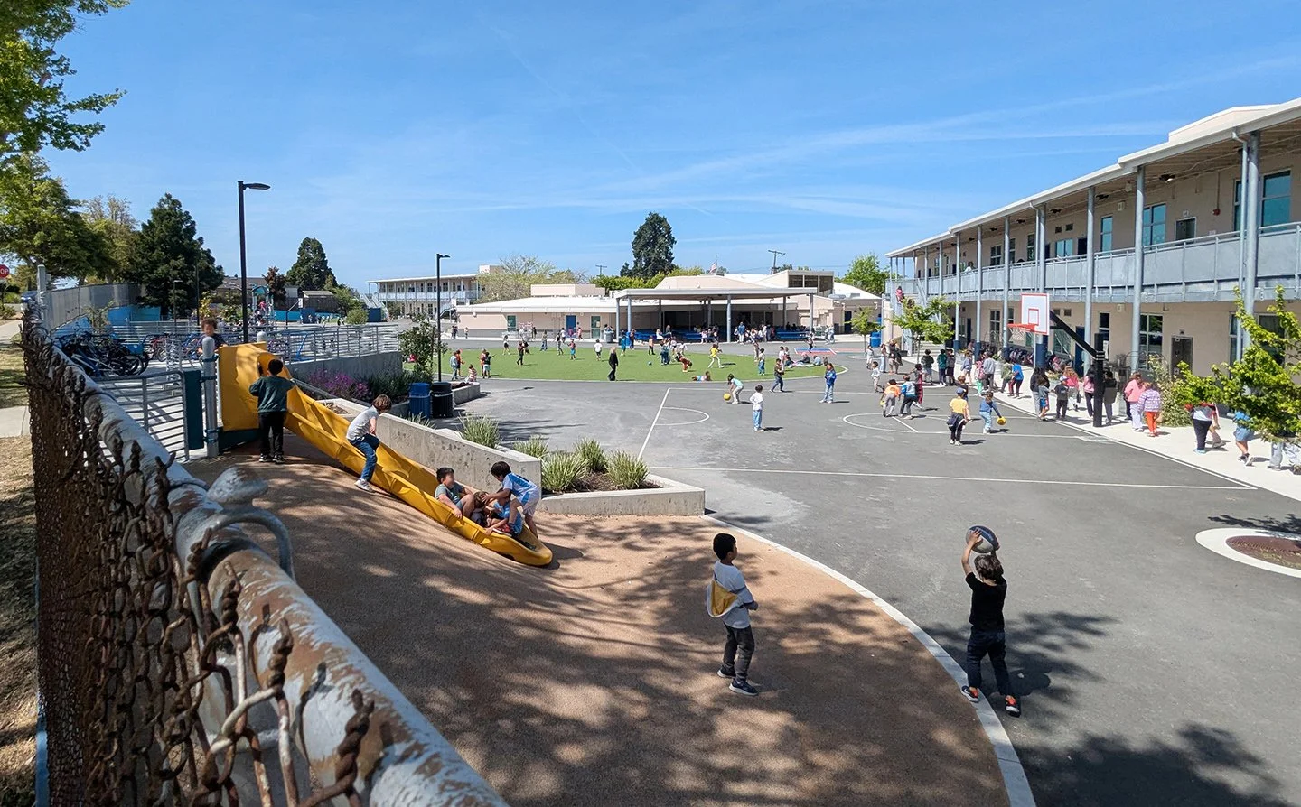 Curving play spaces, open sightlines, and shaded gathering areas organize the campus around movement, visibility, and everyday student interaction.