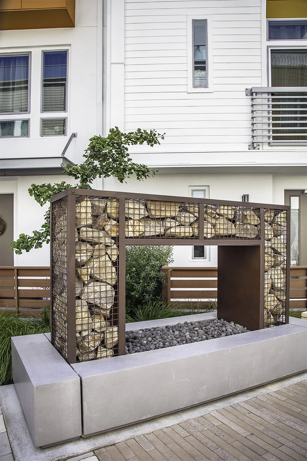 A decorative fireplace element introduces warmth and texture along the paseo, creating an intimate space for social connection.