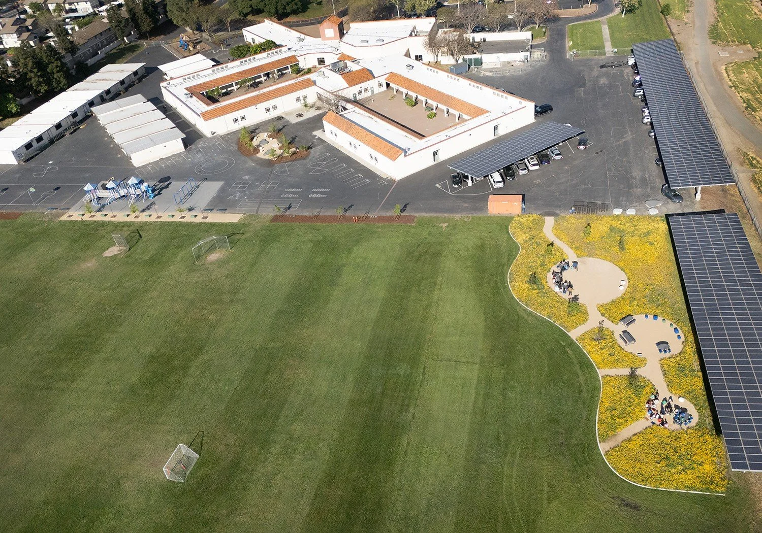 Additional shade trees and seating areas were added along the blacktop edge to provide summer shelter near the play area.