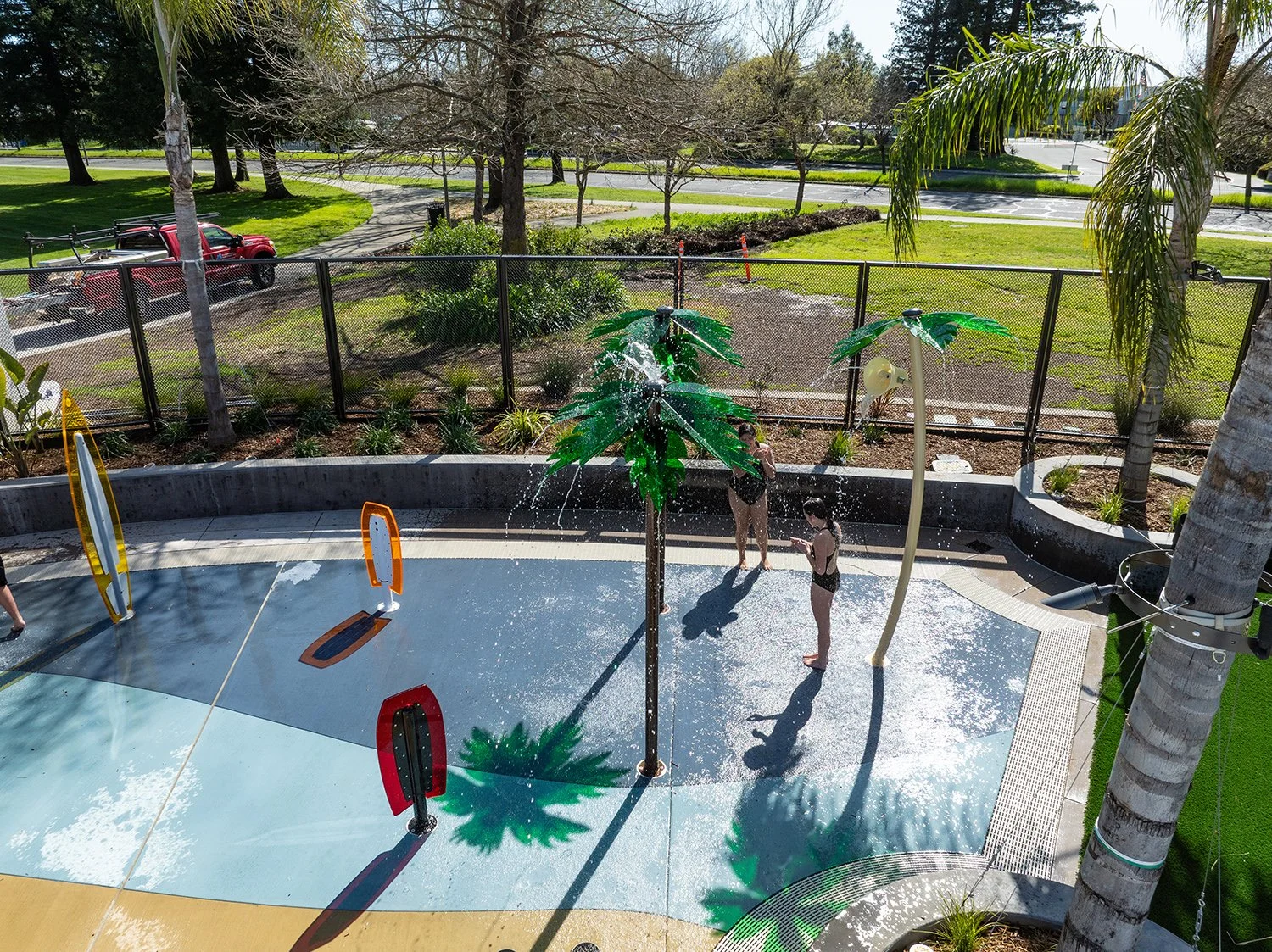 Colorful palm tree sprayers and a border of lush, drought-tolerant plants add to the tropical vibe.