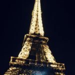 The Eiffel Tower illuminated at night against a dark sky.