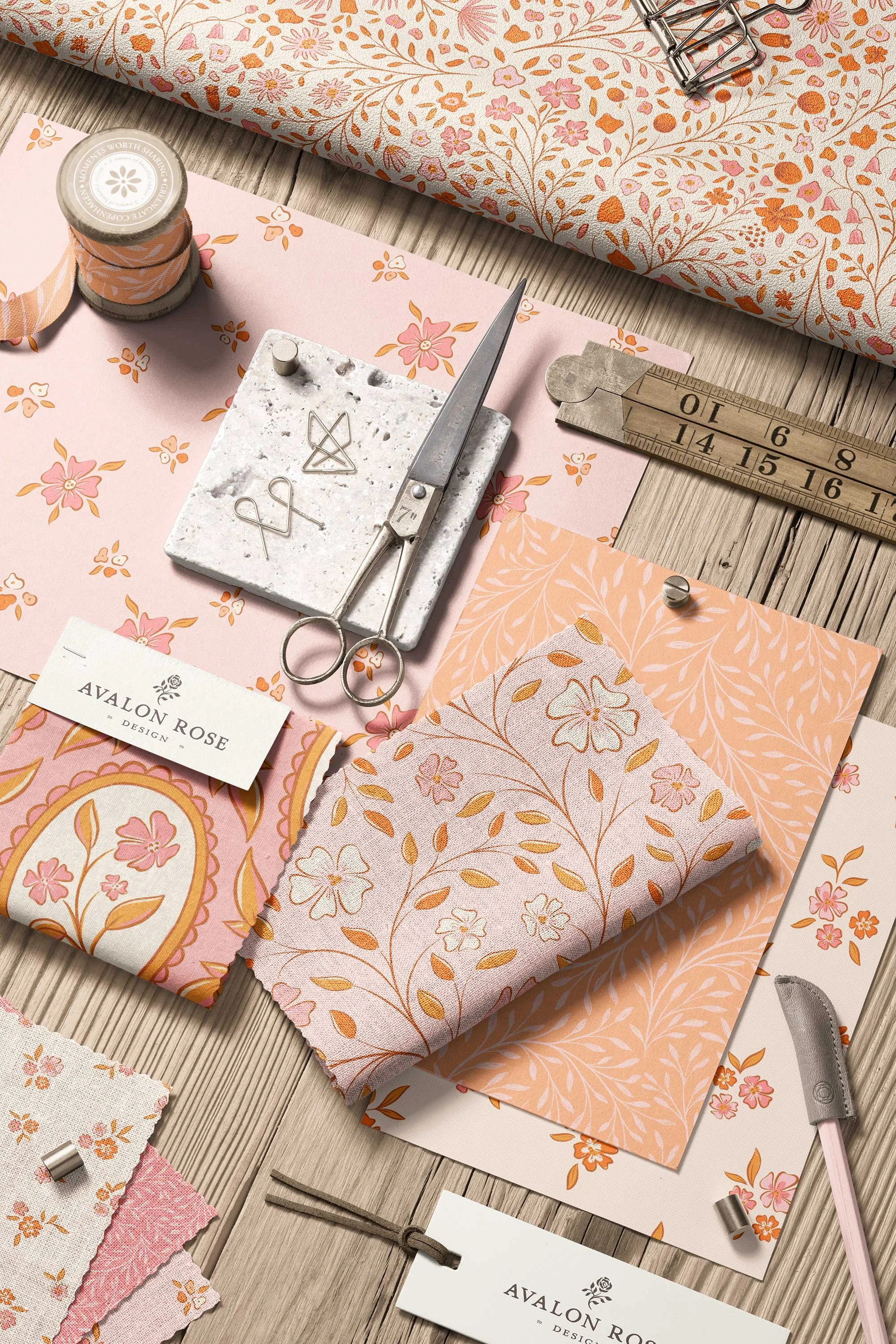 Flat lay of floral patterned fabric, scissors, ruler, and fabric swatches in pink and peach tones, with a small branded card reading 'Avalon Rose'.