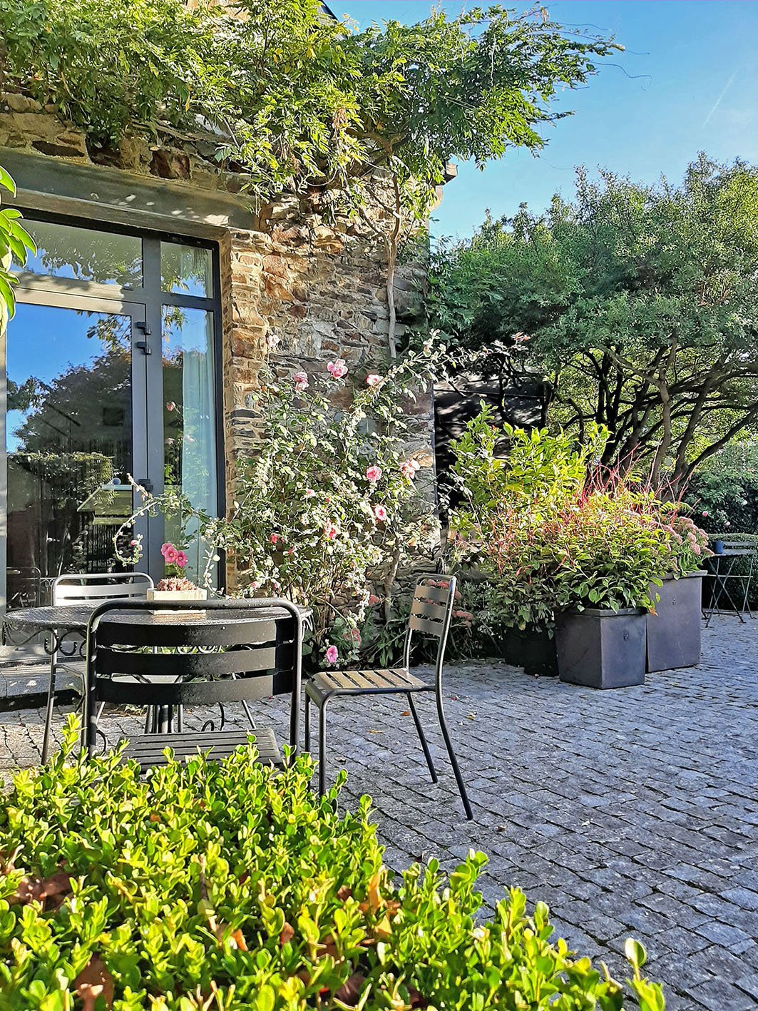 Le jardin de l'atelier Callarec à Troguéry dans les Côtes d'Armor, cour pavée, été indien