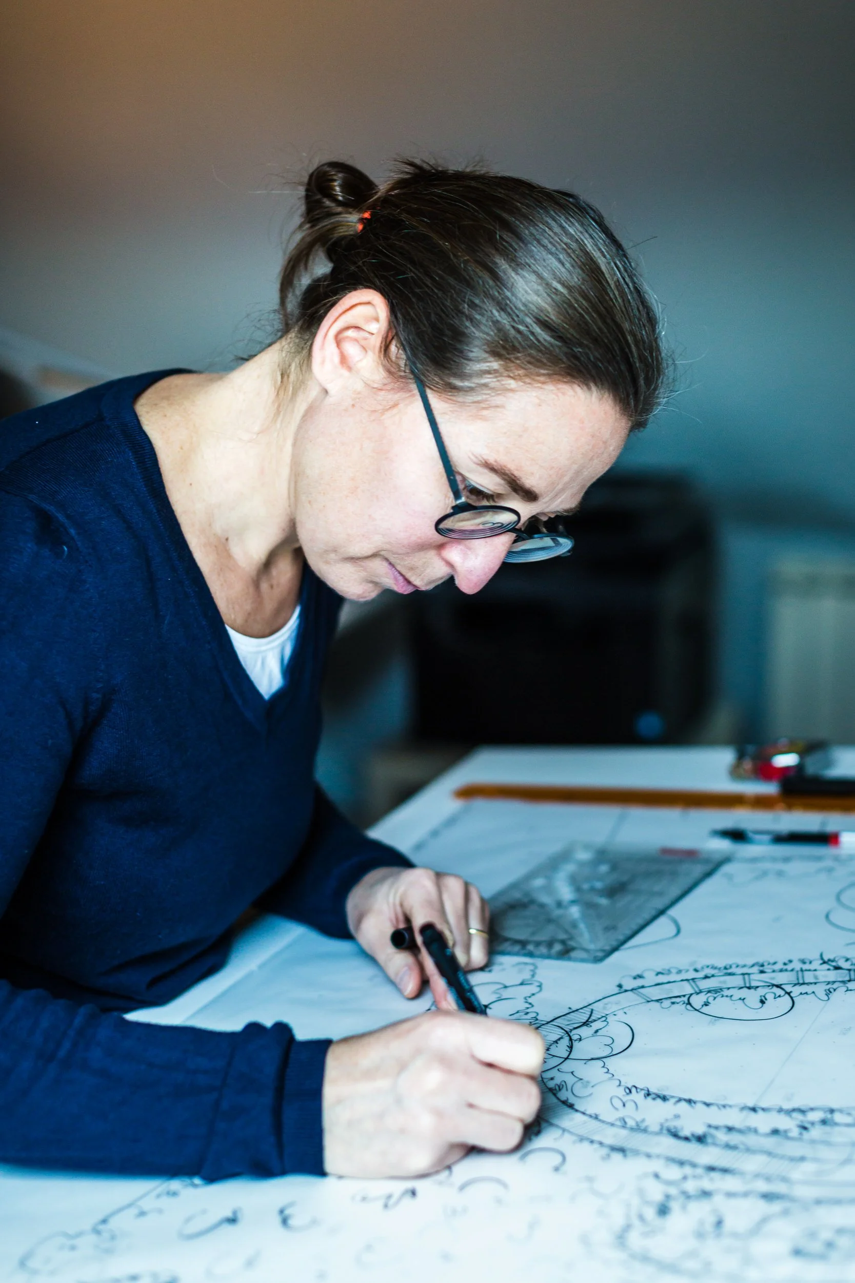 Cécile Callarec dessinant un plan de jardin sur calque dans le bureau d'étude de l'Atelier Callarec.