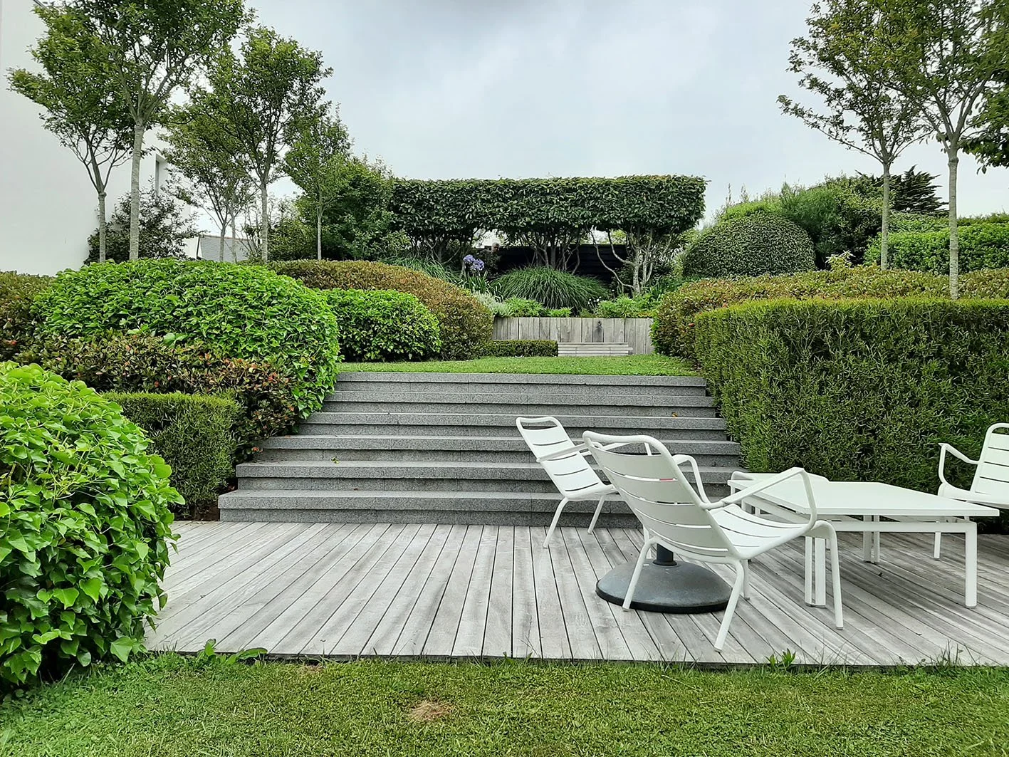 jardin paysager à Locquirec dans le Finistère avec terrasse en bois, marches en granit et végétation adaptée au bord de mer.