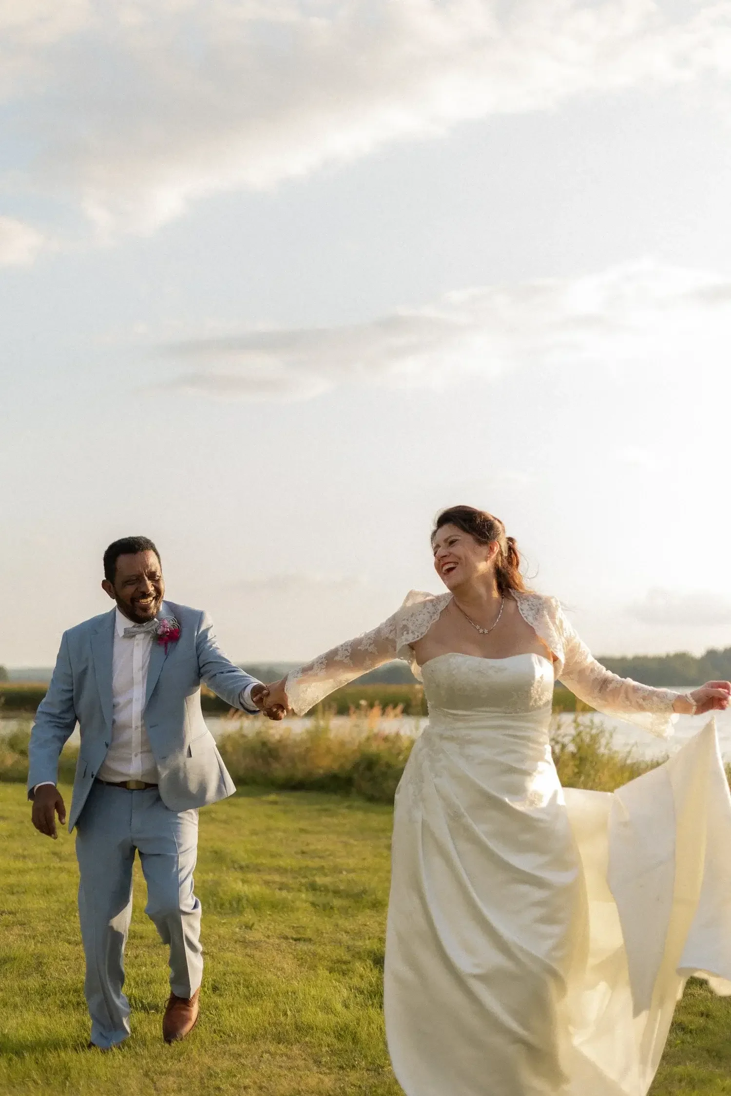 Hääkuva ulkona: pari kävelee nurmikolla auringonpaisteessa