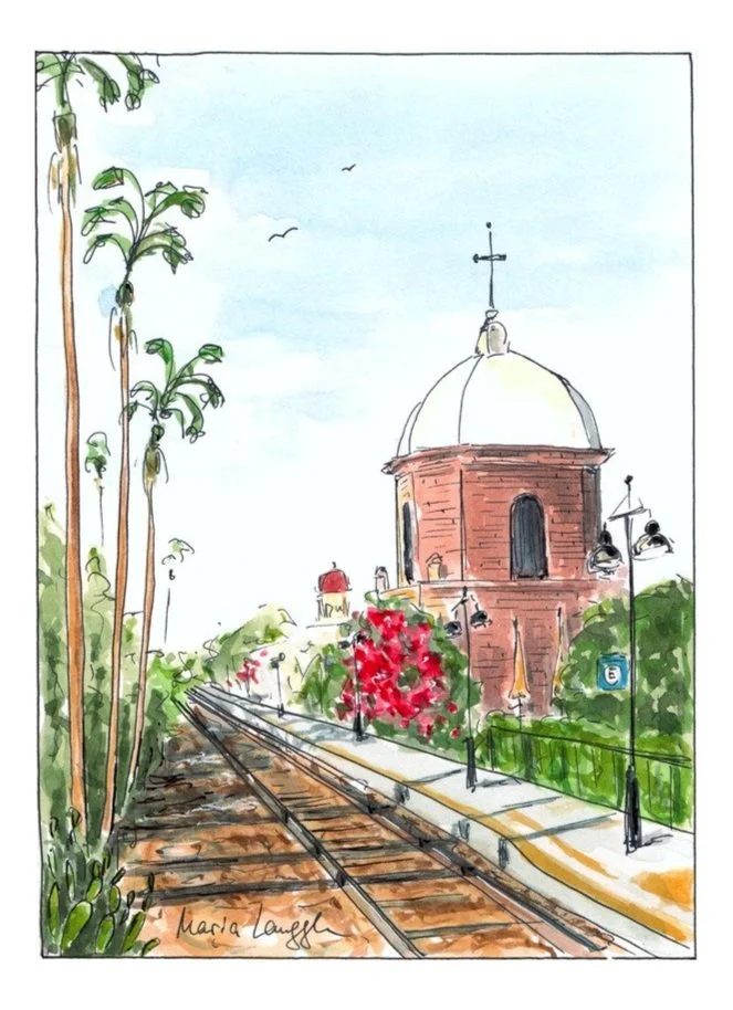 A watercolor painting of a street with railroad tracks, trees, and a red brick building with a white dome and a cross on top. The scene includes street lamps and blooming bushes.