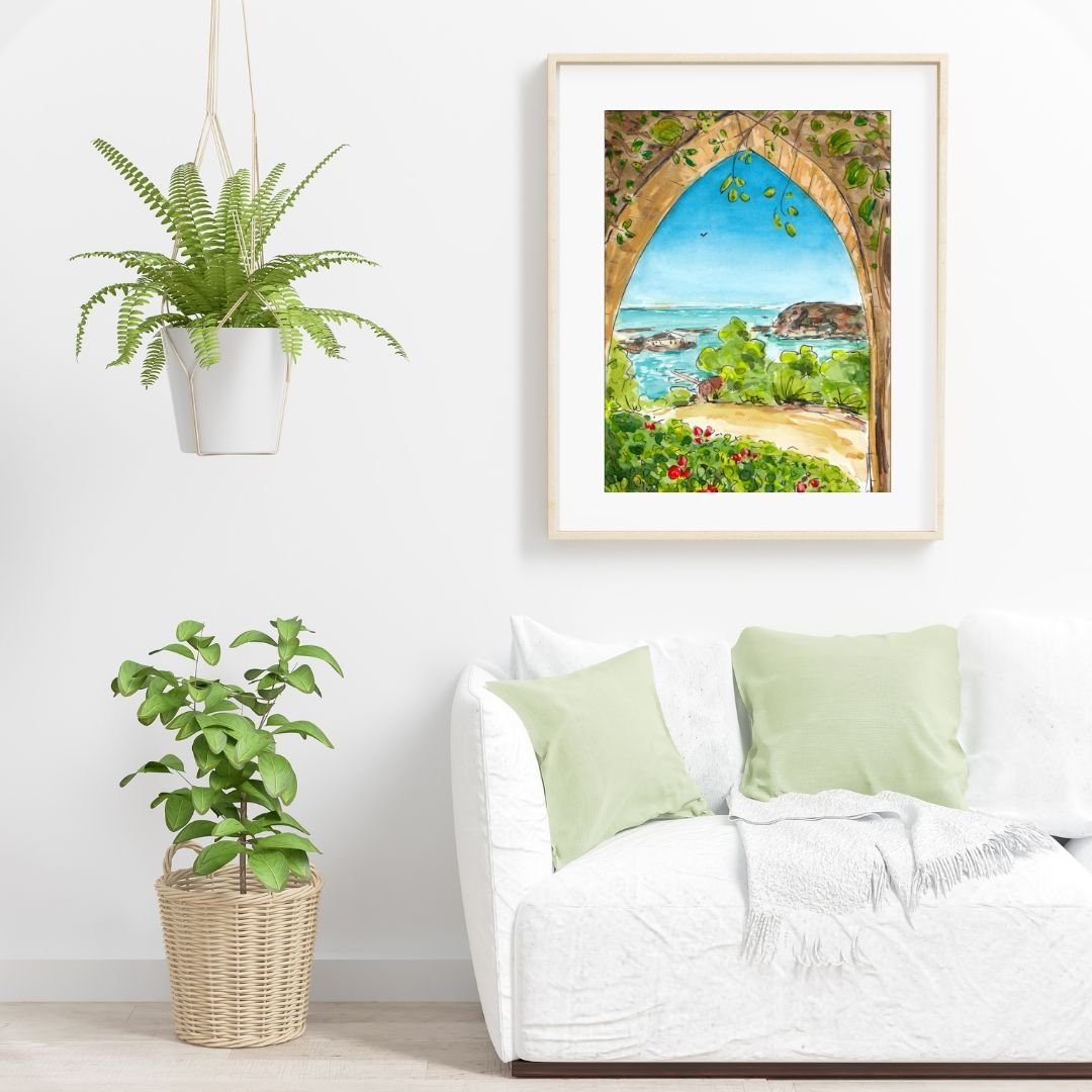 Living room with white sofa, pale green pillows, potted plant, wall art of a seaside landscape, and a hanging fern plant.