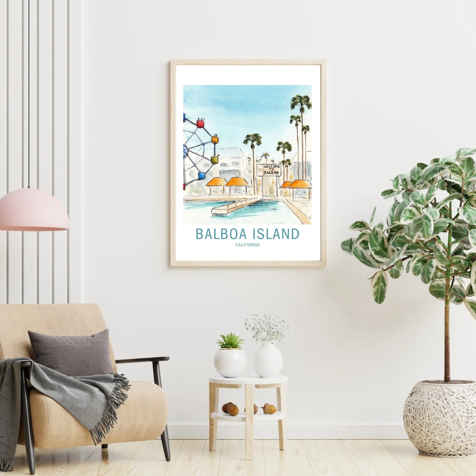 Decorative interior with a framed watercolor print of Balboa Island, California, on a white wall. The room features a beige armchair with a gray pillow and blanket, a small white side table with two white vases and a small potted plant, a large potted plant on the right, and a pink hanging lamp on the left.