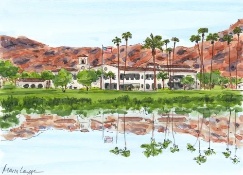 Water reflection of houses, palm trees, and mountains with a cloudy sky.