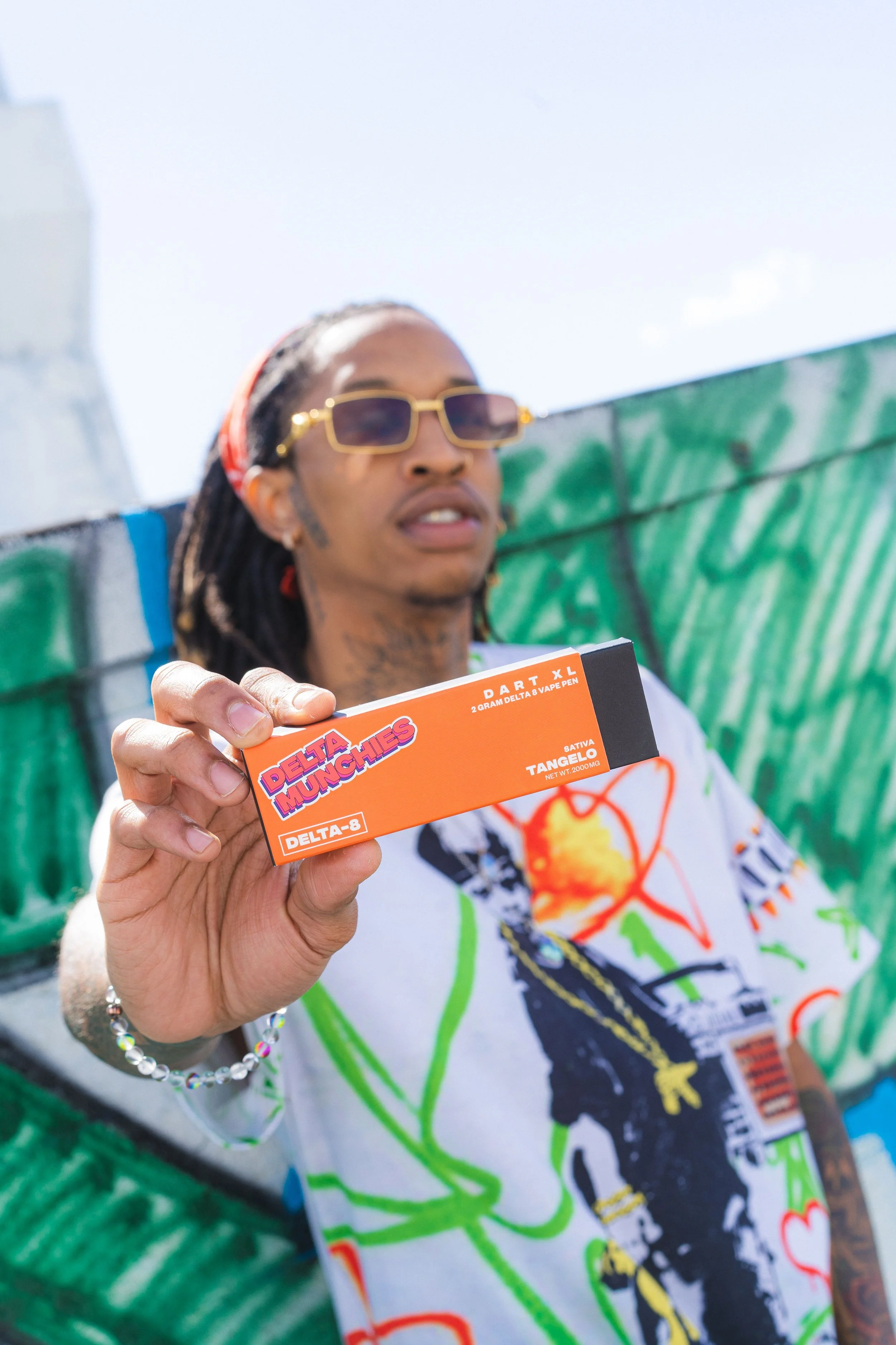 Person holding a Delta Munchies Delta-8 vape pen package in an urban setting.