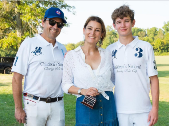 A member of the Founders Auxiliary poses with players and their prizes post-match at the 2025 Charity Polo Cup.