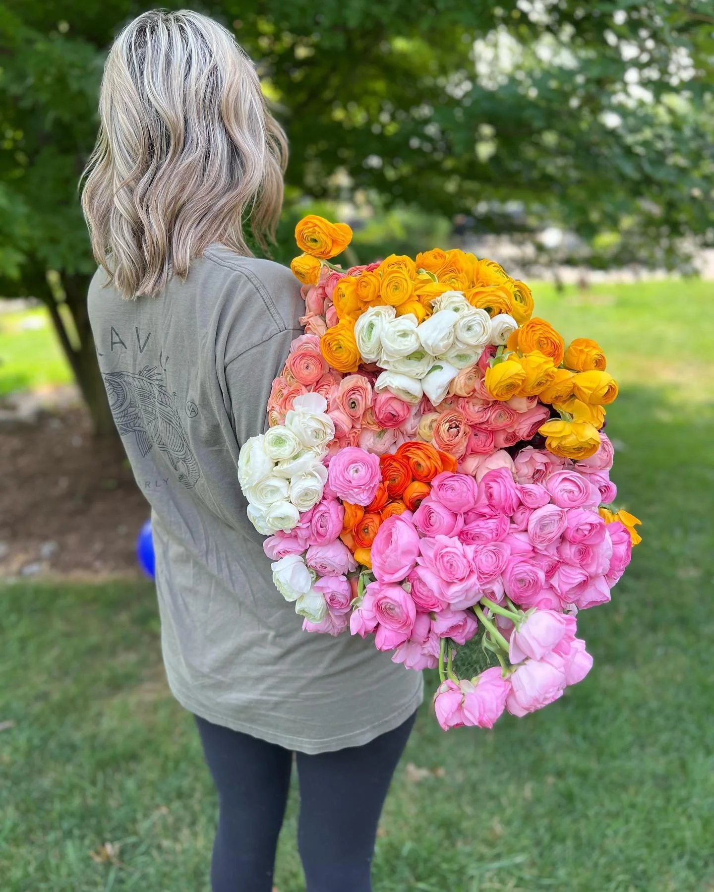 Person with flowers, colorful bouquet, greenery background