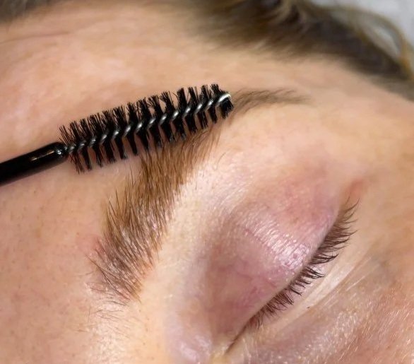 Close-up of a closed eye showing the eyebrow, eyelash, and skin texture.