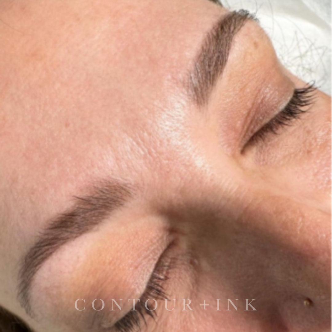 Close-up of a person's face with closed eyes, well-groomed eyebrows, long eyelashes, and clear skin.