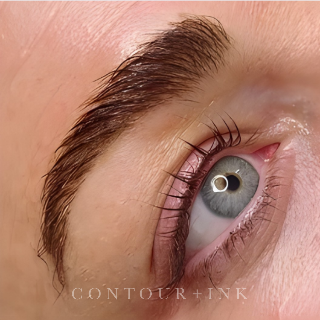 Close-up of a person's eye, showing detailed eyelashes, eyebrows, and eye color, with makeup and skin texture visible.