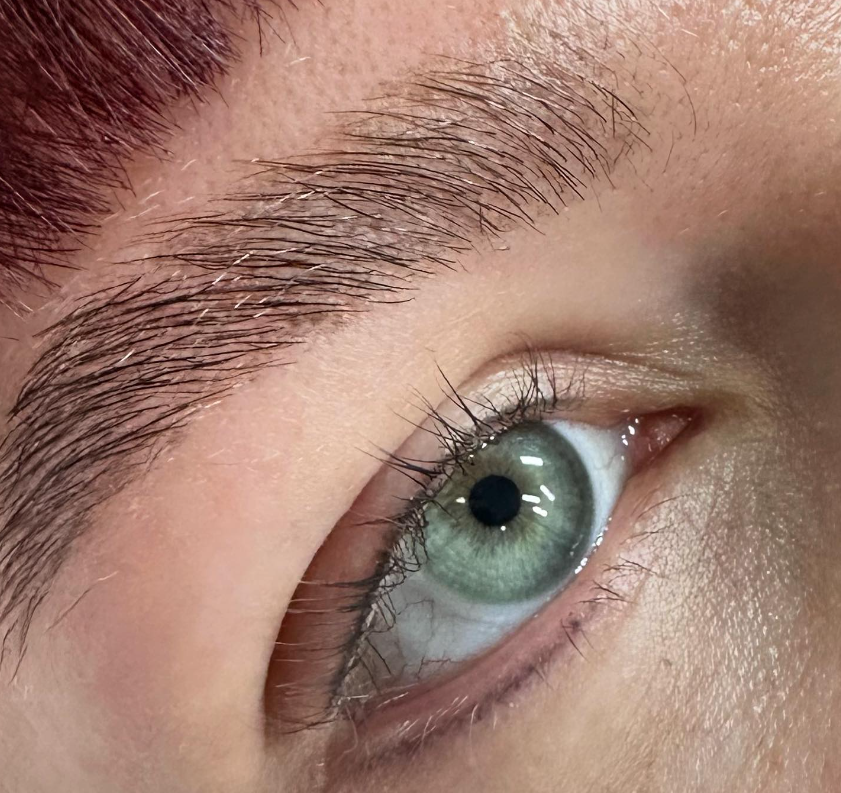 Close-up of a human eye with green iris and long eyelashes.