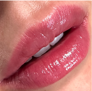 Close-up of slightly parted lips with shiny, pink lipstick or gloss.