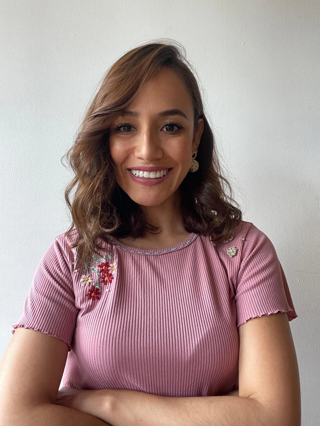 A woman with shoulder-length wavy brown hair. She is a Spanish tutor native from Latin America. She is profesional, kind and patiente. 