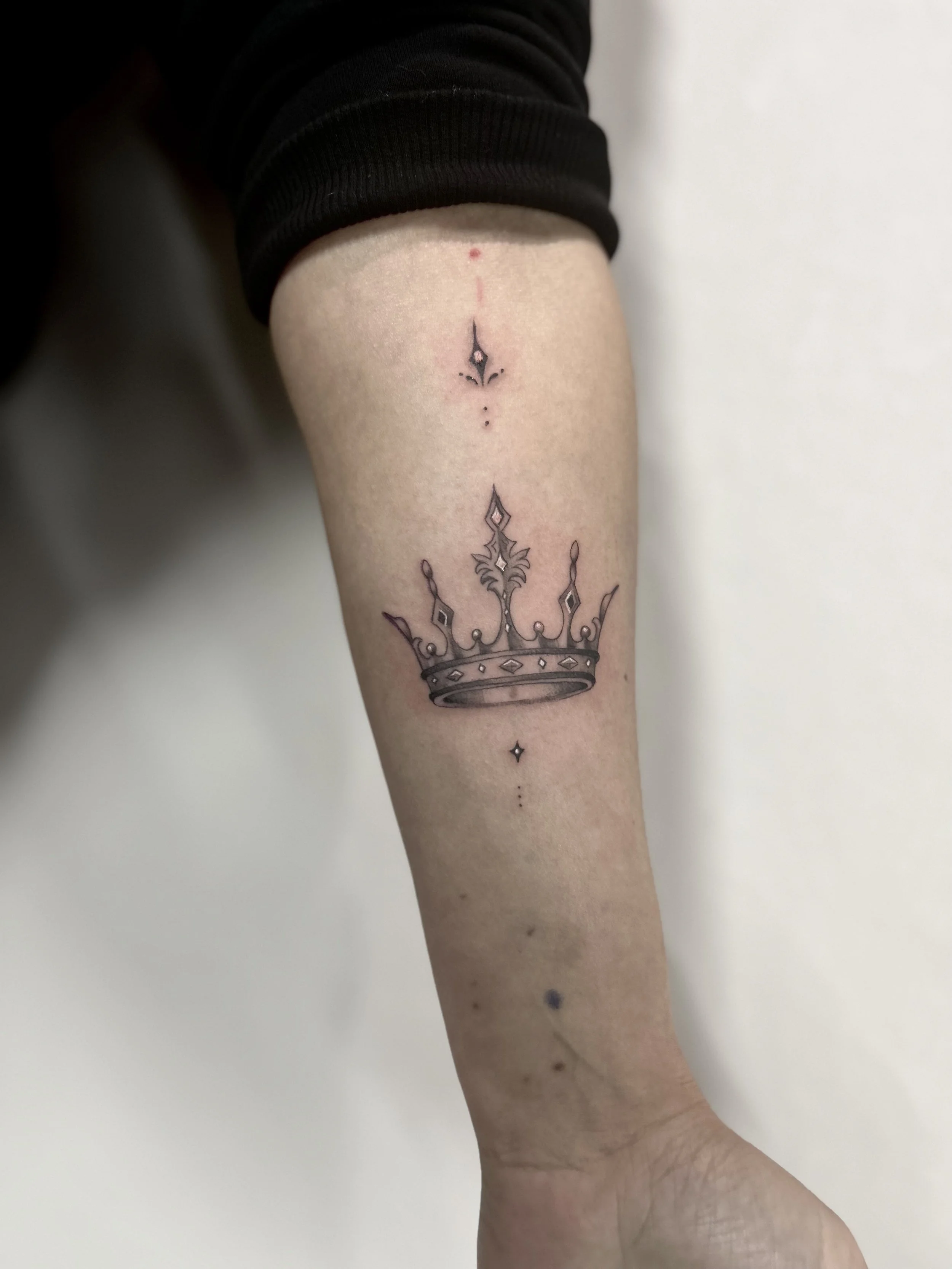 Tattoo of a crown with ornate details.