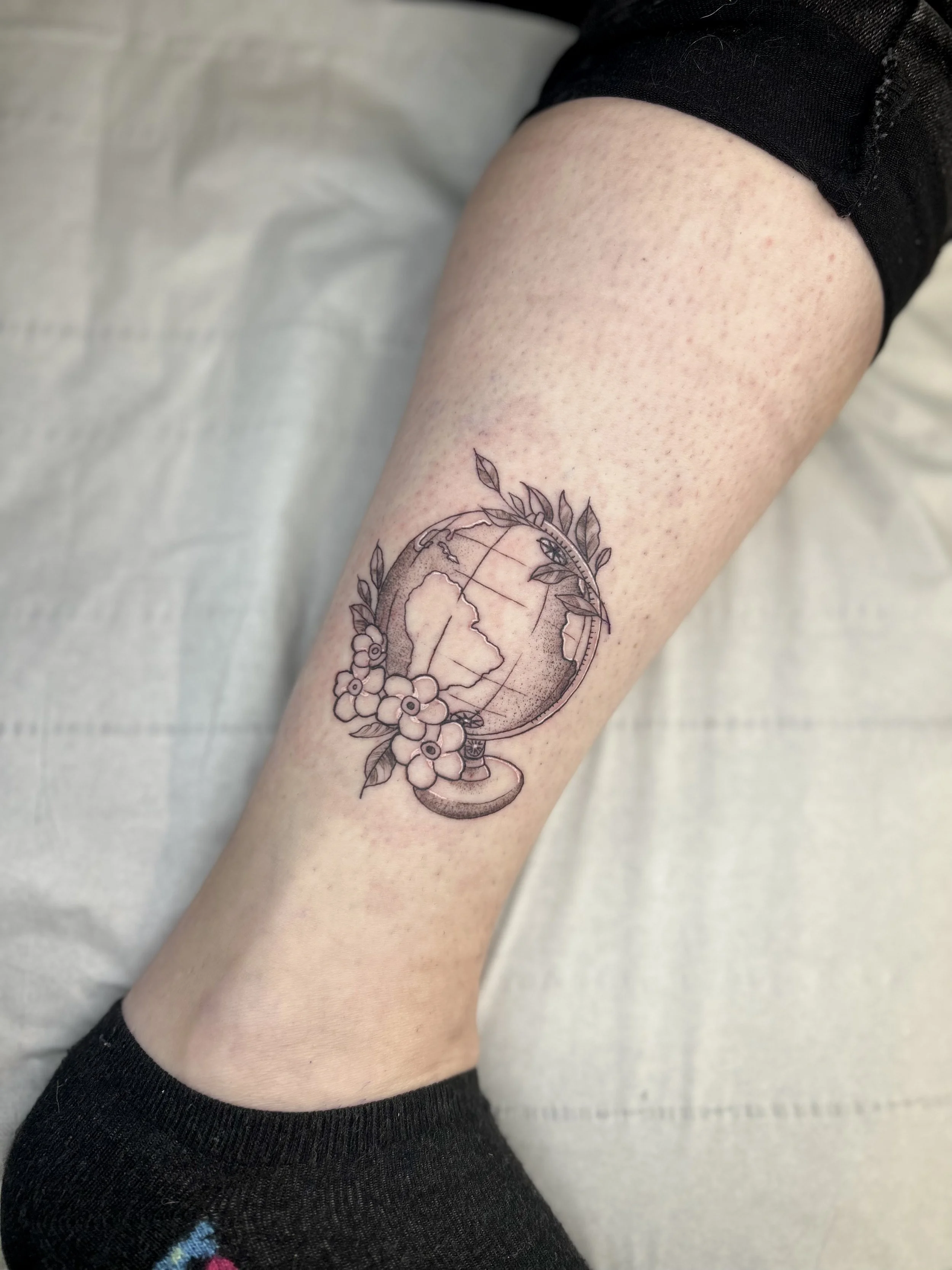 Tattoo of a globe with floral elements.