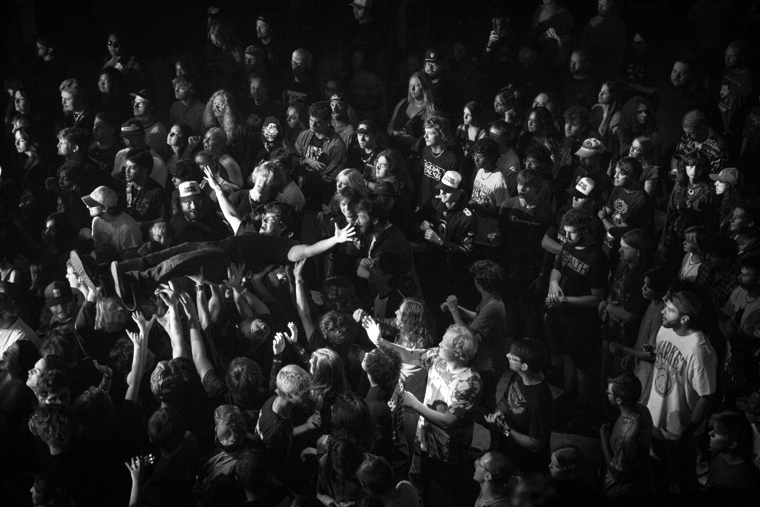 A crowd of people at a concert at Brooklyn Bowl Nashville, with one person crowd surfing above others in a black and white photo.
