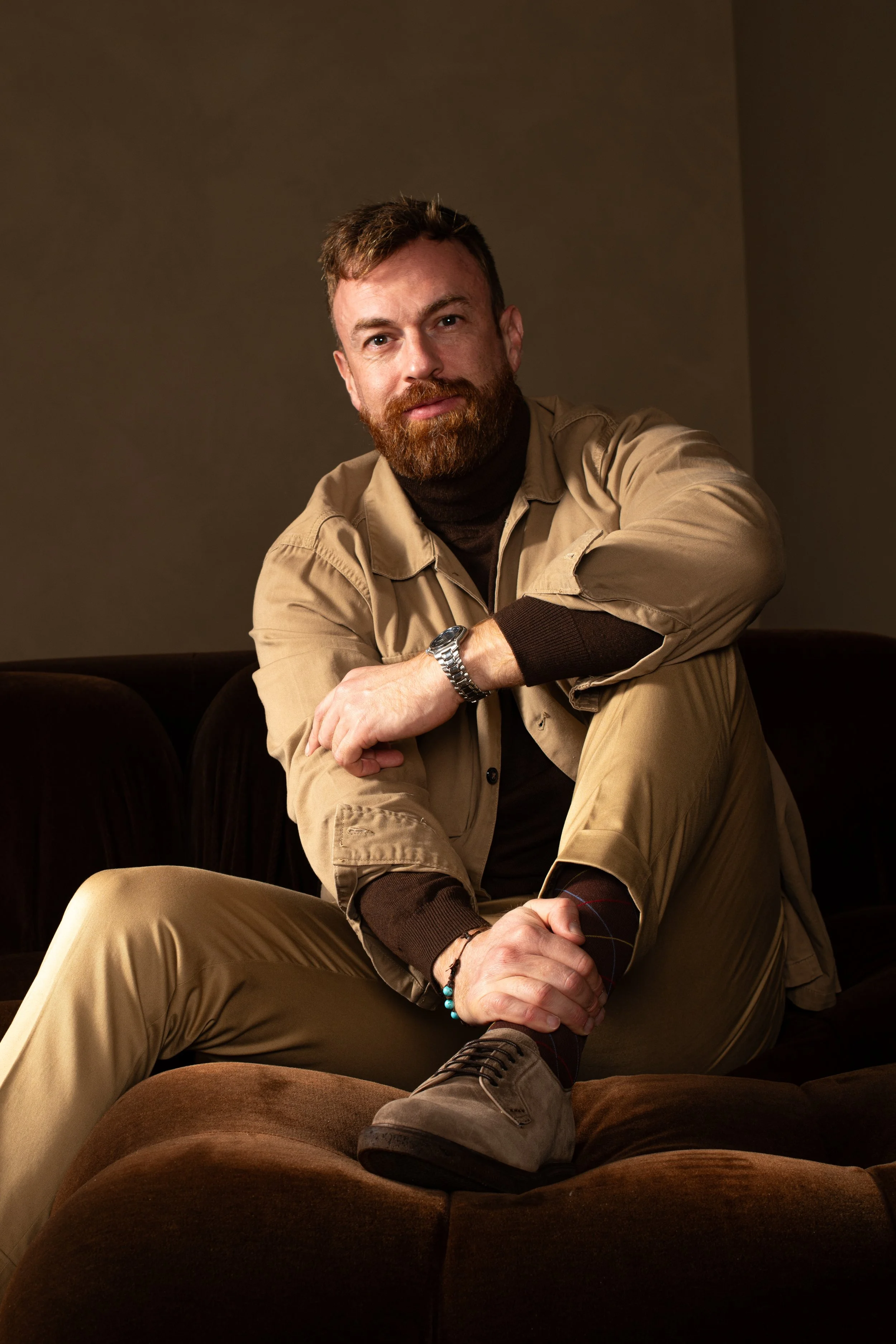 Il fotografo piacentino Andrea Landini seduto su un divano in posizione rilassata e accogliente.