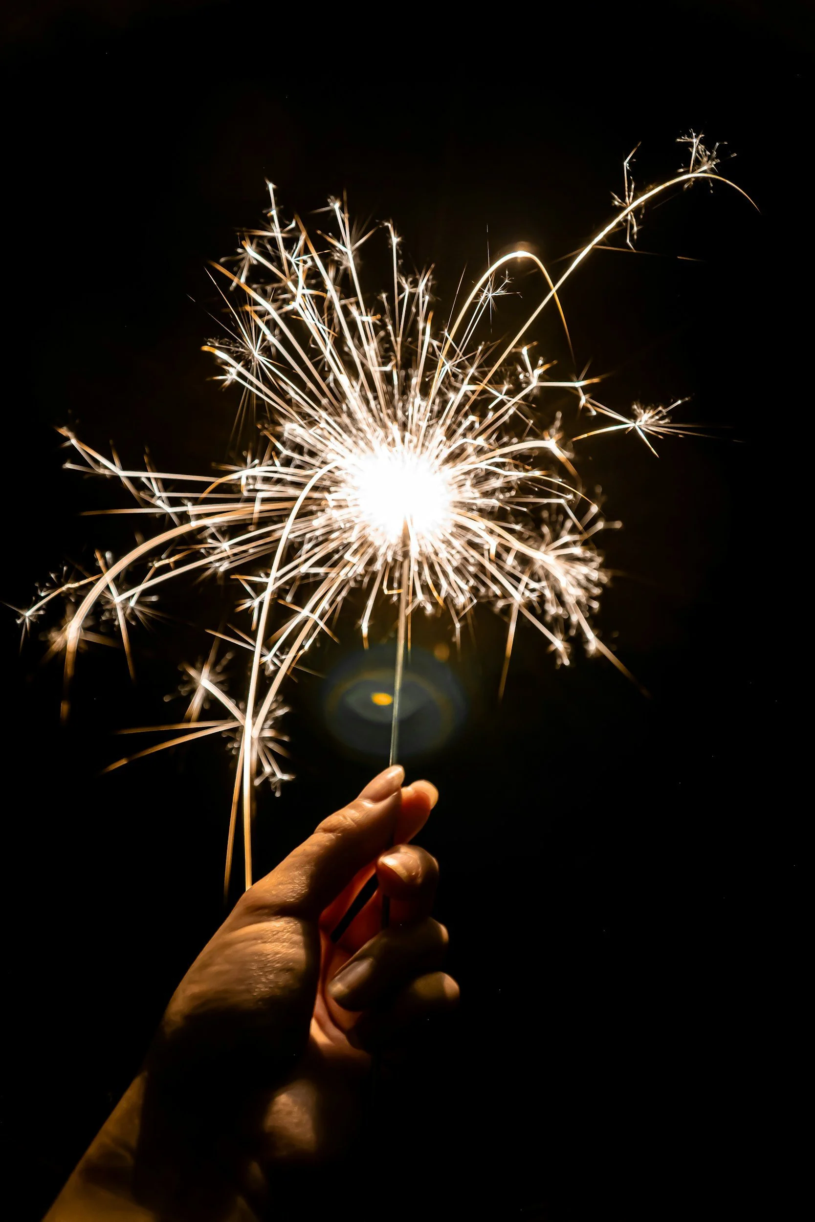 Person holding a sparkler during an outdoor celebration, symbolizing hope and personal growth.