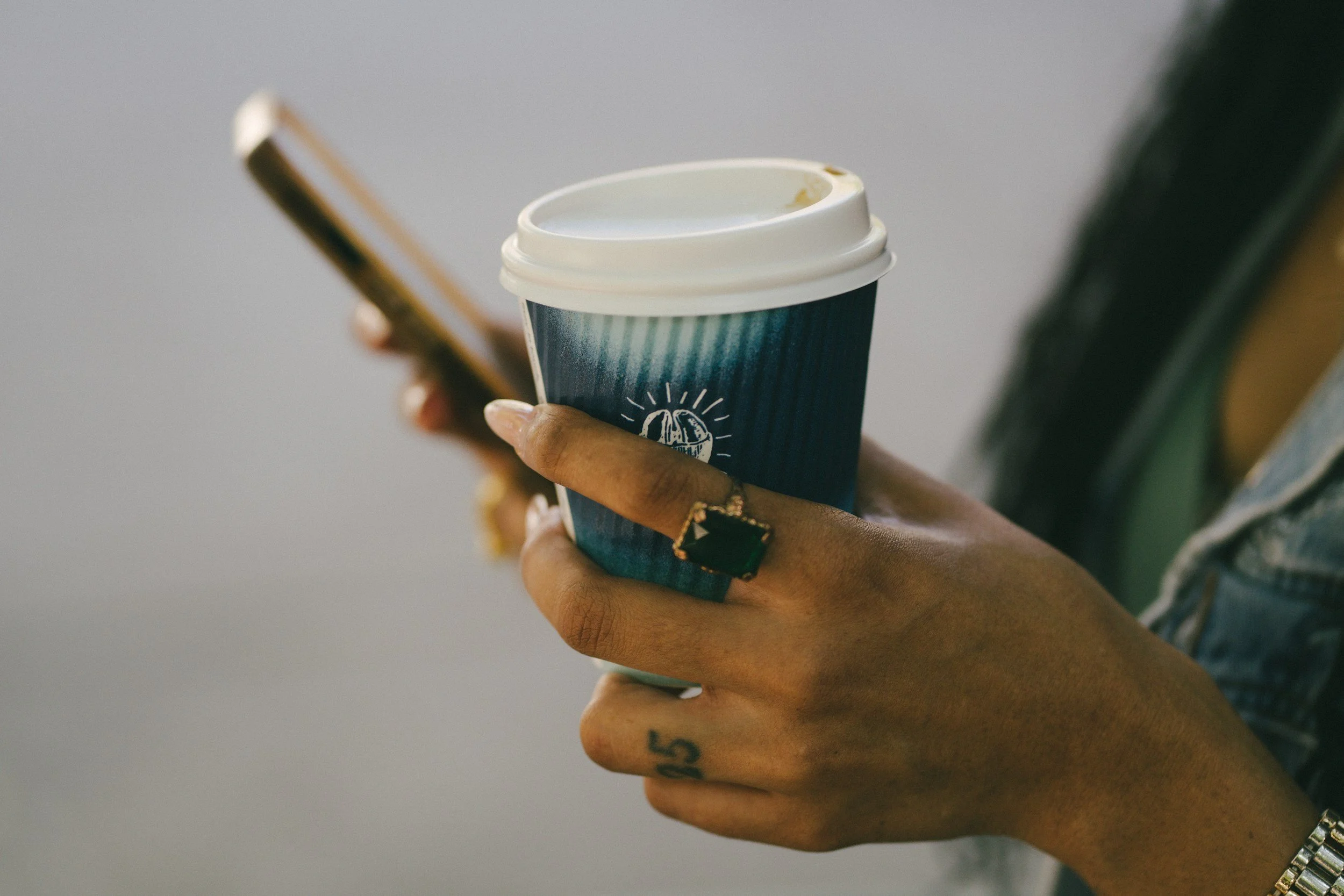 woman with phone in hand and coffee