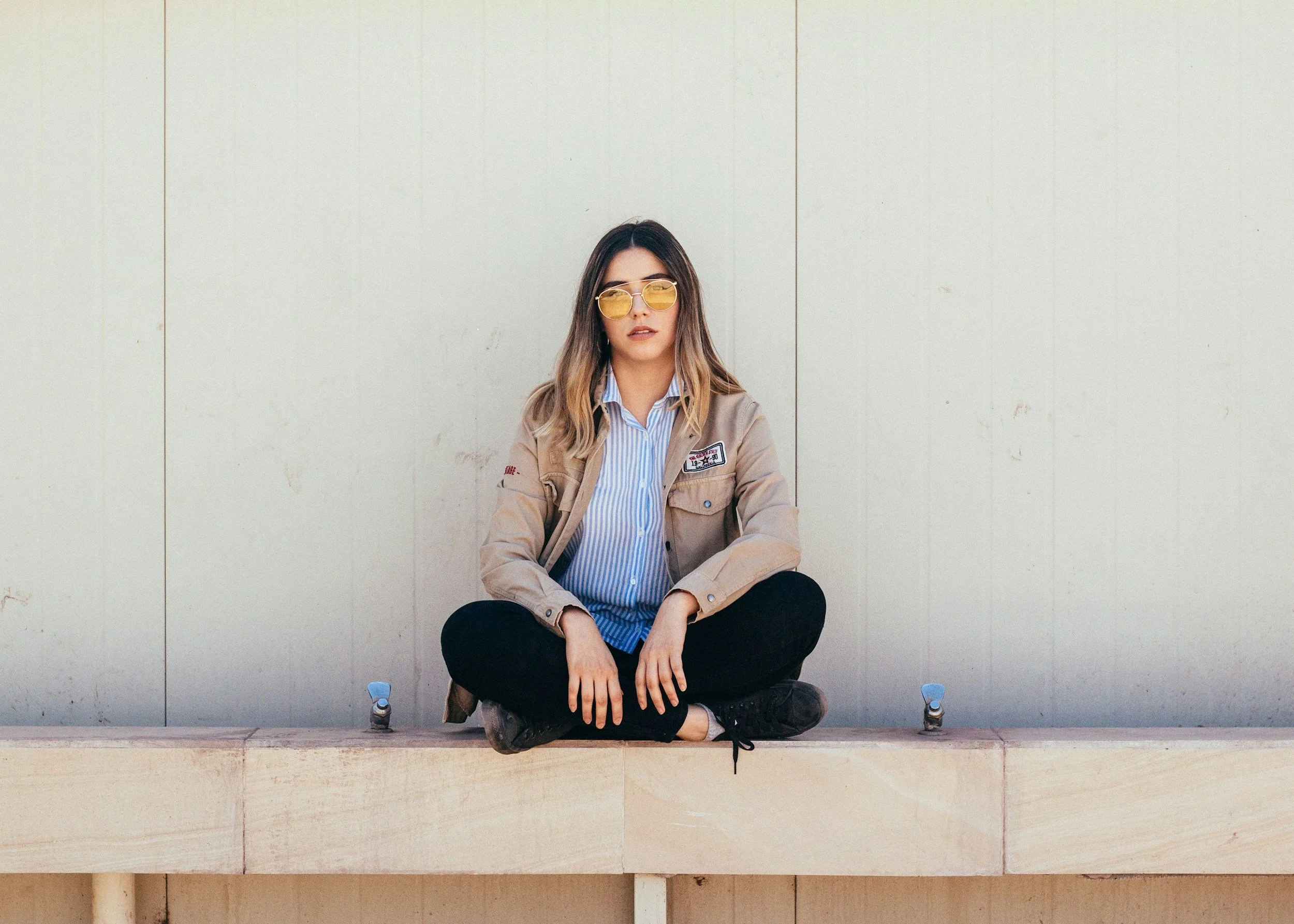 Woman sitting on the ground with  yellow glasses feeling happy