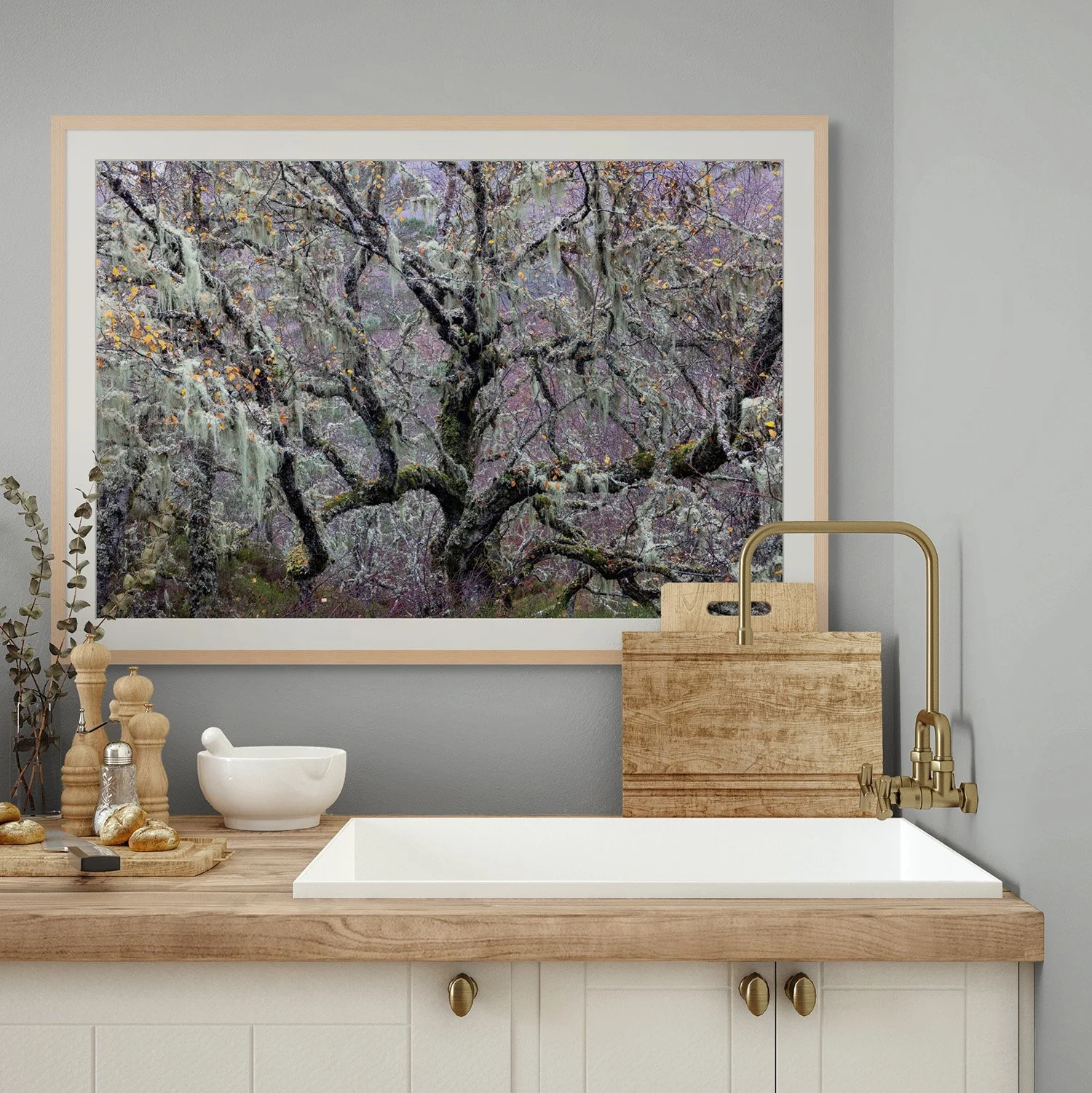 a fine art photograph of autumn woodland on a wall above a kitchen sink with wooden counter and chopping board