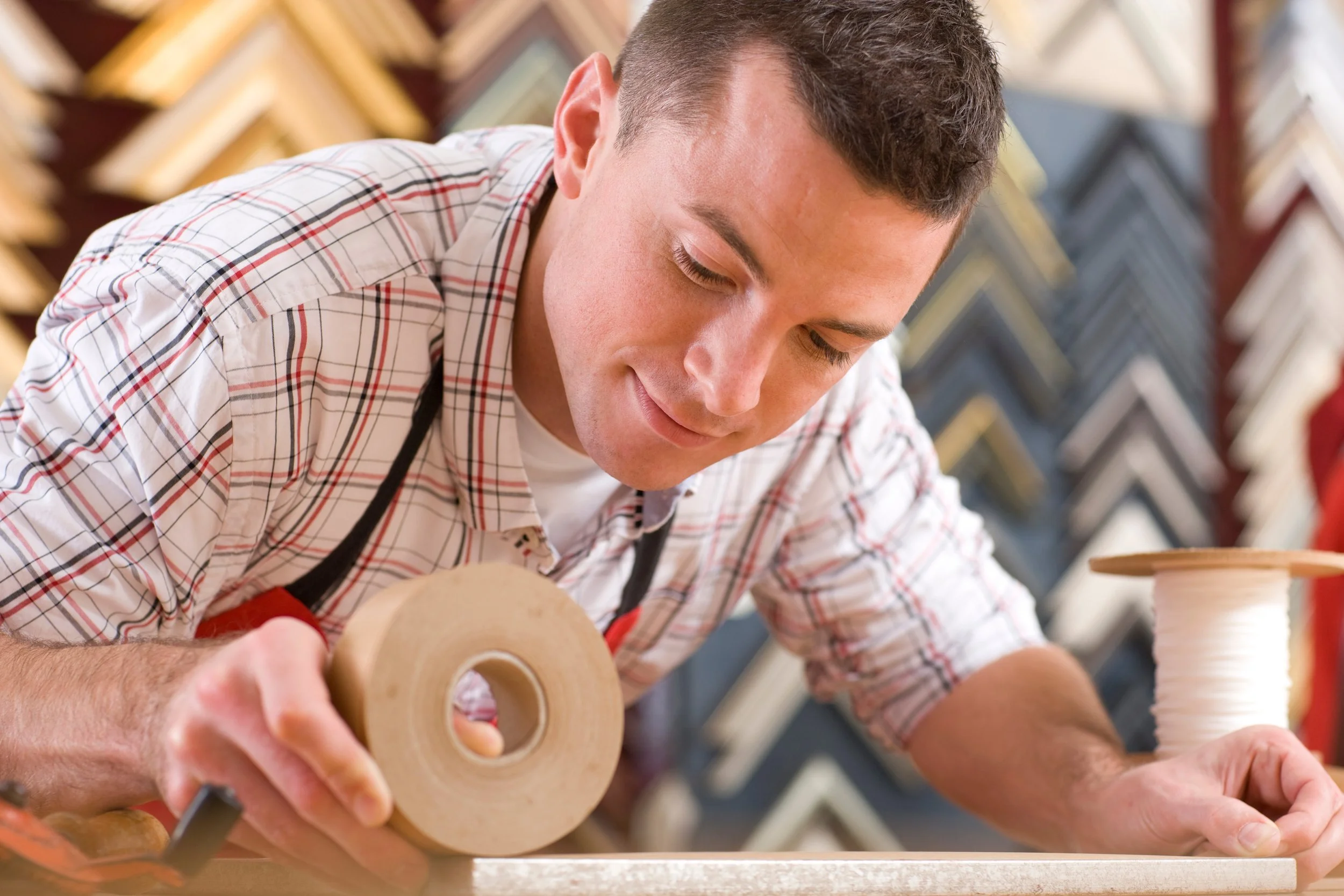 a man preparing a framed print in his workshop
